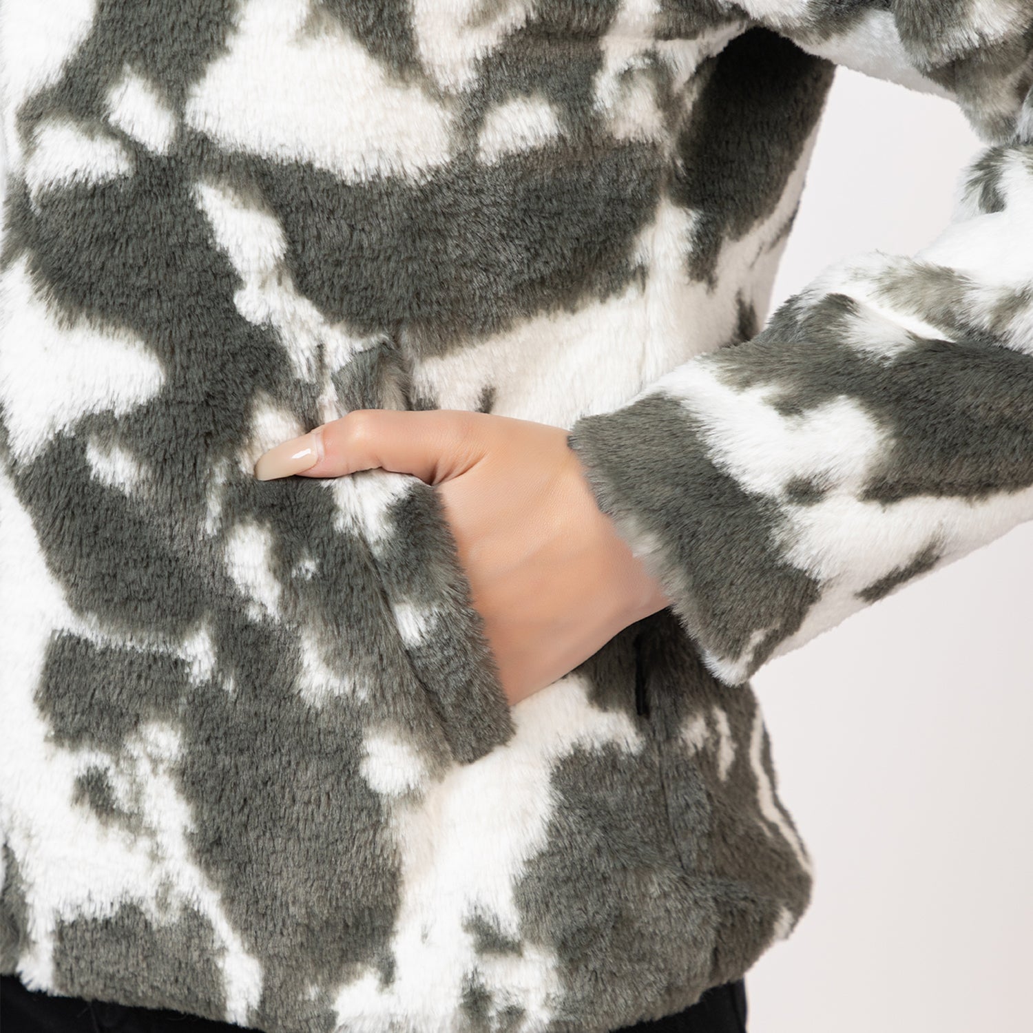 Close-up of a person wearing a gray and white patterned sweater with a hand visible. Amoldo